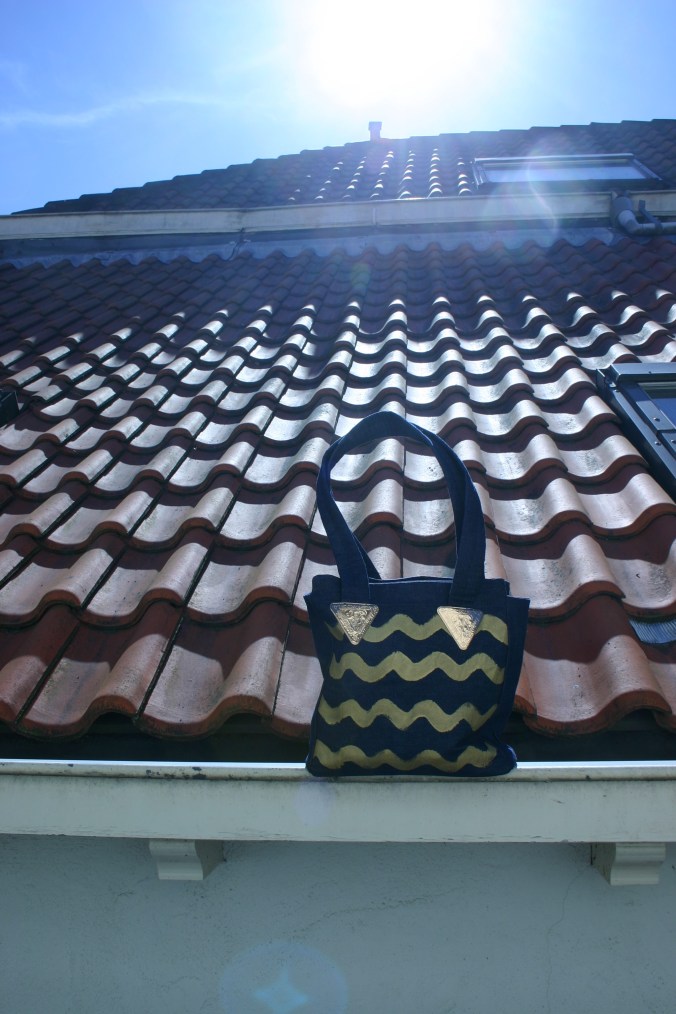 diy denim bag with painted gold colored waves on the rooftops in Kloksteeg Delft Netherlands