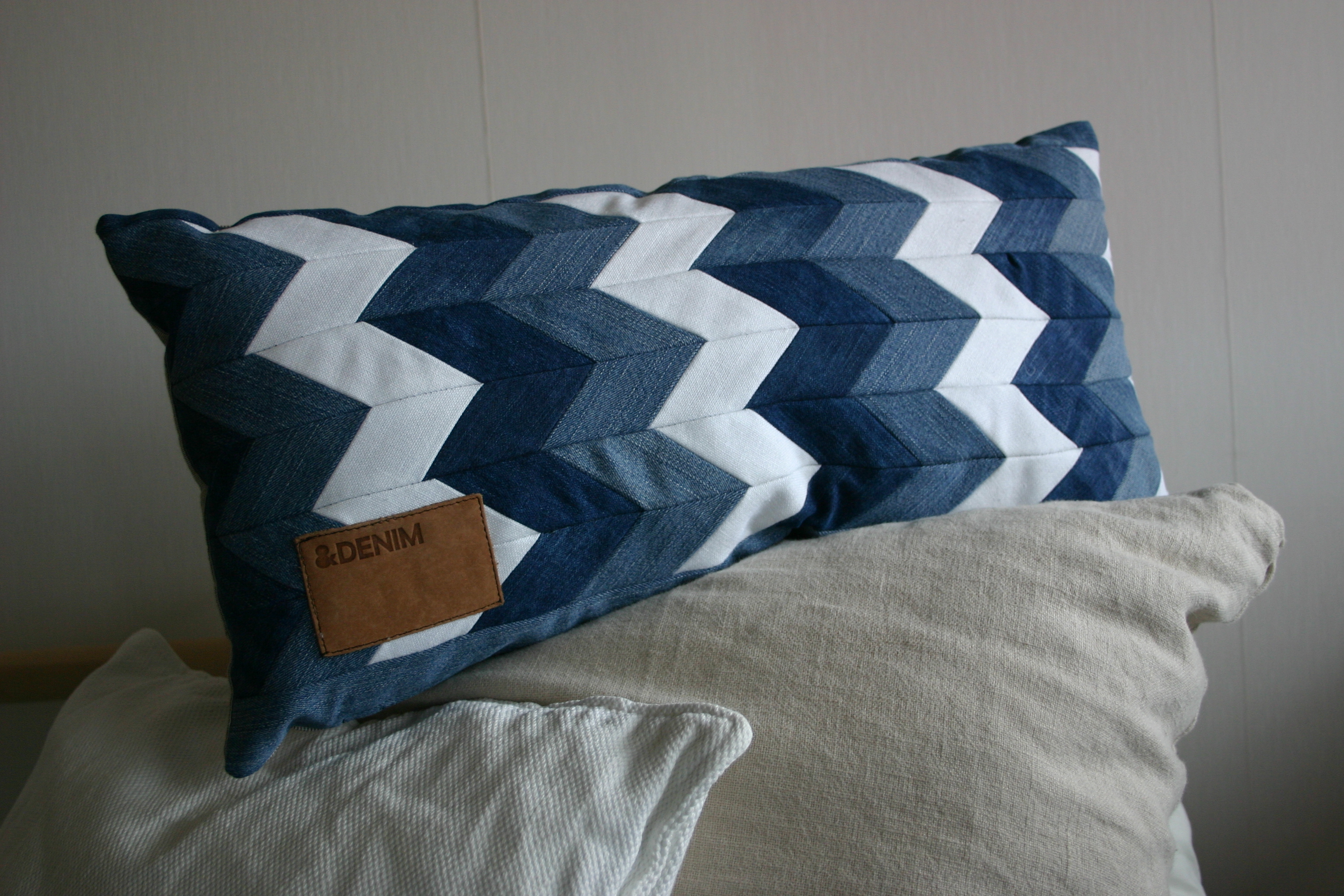diy chevron pattern denim cushion out of old jeans and linen fabric, decorated with original patch from the recycled jeans